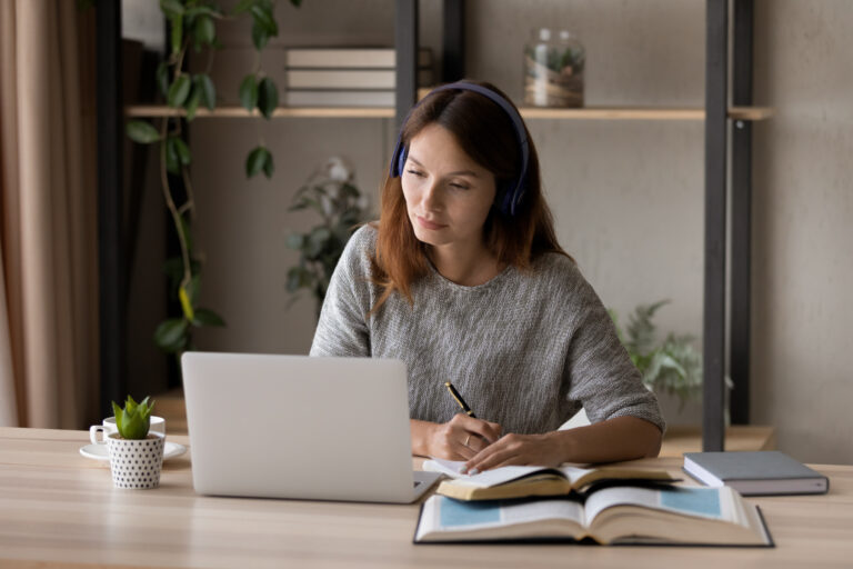 Studentin lernt Deutsch mit Laptop und Lehrbuch