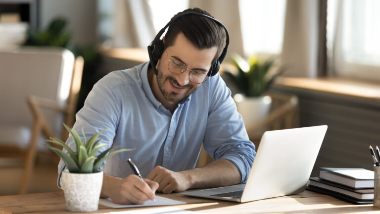 Teilnehmer mit Headset macht sich Notizen im Online-Deutschkurs